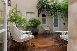 Eine Terrasse im Freien mit Holzboden, weißen Korbstühlen und einem Blumentopf.