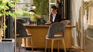 A reception desk with two chairs, a potted plant, and a desk lamp. - Millésime Hôtel (Paris)