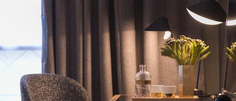 Een moderne hotelkamer met een houten bureau, een stoel, een lamp en een vaas met bloemen.