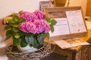 A potted hydrangea plant with a rustic nest base, a wooden signboard with text, and a framed picture on a wooden table. - Pension Daniel (Lech am Arlberg)