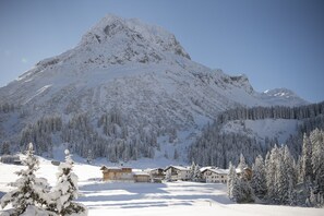 A snow-covered mountain with a chalet-style building in the foreground. - Pension Daniel (Lech am Arlberg)