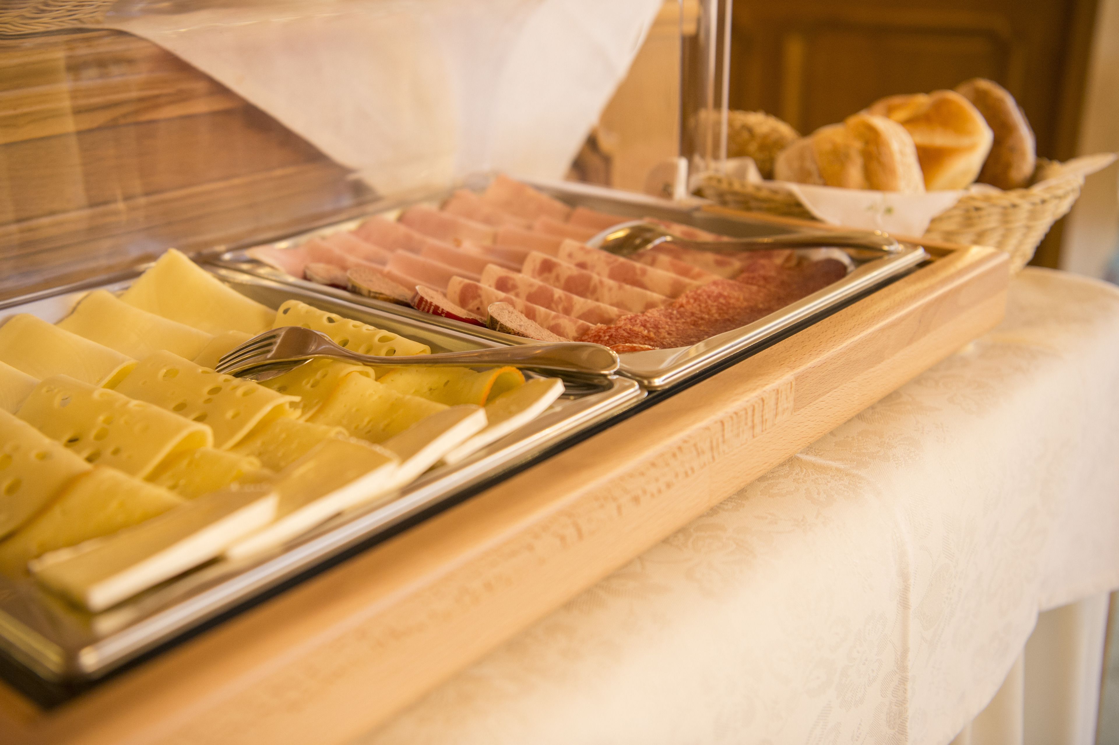 A buffet with various cheeses and meats.