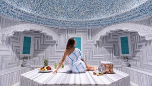 Une pièce dotée d’un plafond orné de motifs, d’un espace de détente central avec une table, et d’éléments décoratifs.