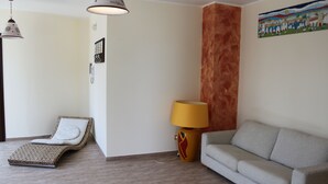 A room with a lounge chair, a sofa, a lamp, and a painting on the wall. - Locanda Del Drago (Monreale)