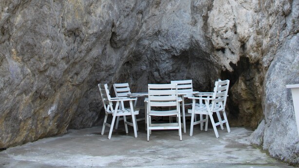 A rock formation with a table and chairs set up against it. - Locanda Del Drago (Monreale)