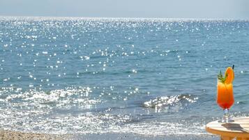 A beach view with a drink on a table and an open book.