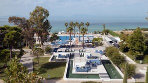 A resort with a pool area, lounge chairs, and a view of the sea.