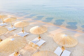 A beach with clear water, rows of white lounge chairs, and straw umbrellas. - Potidea Palace Hotel - All inclusive (Nea Propontida)