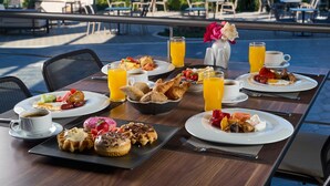 A breakfast table with various dishes, drinks, and a view of the ocean. - Potidea Palace Hotel - All inclusive (Nea Propontida)