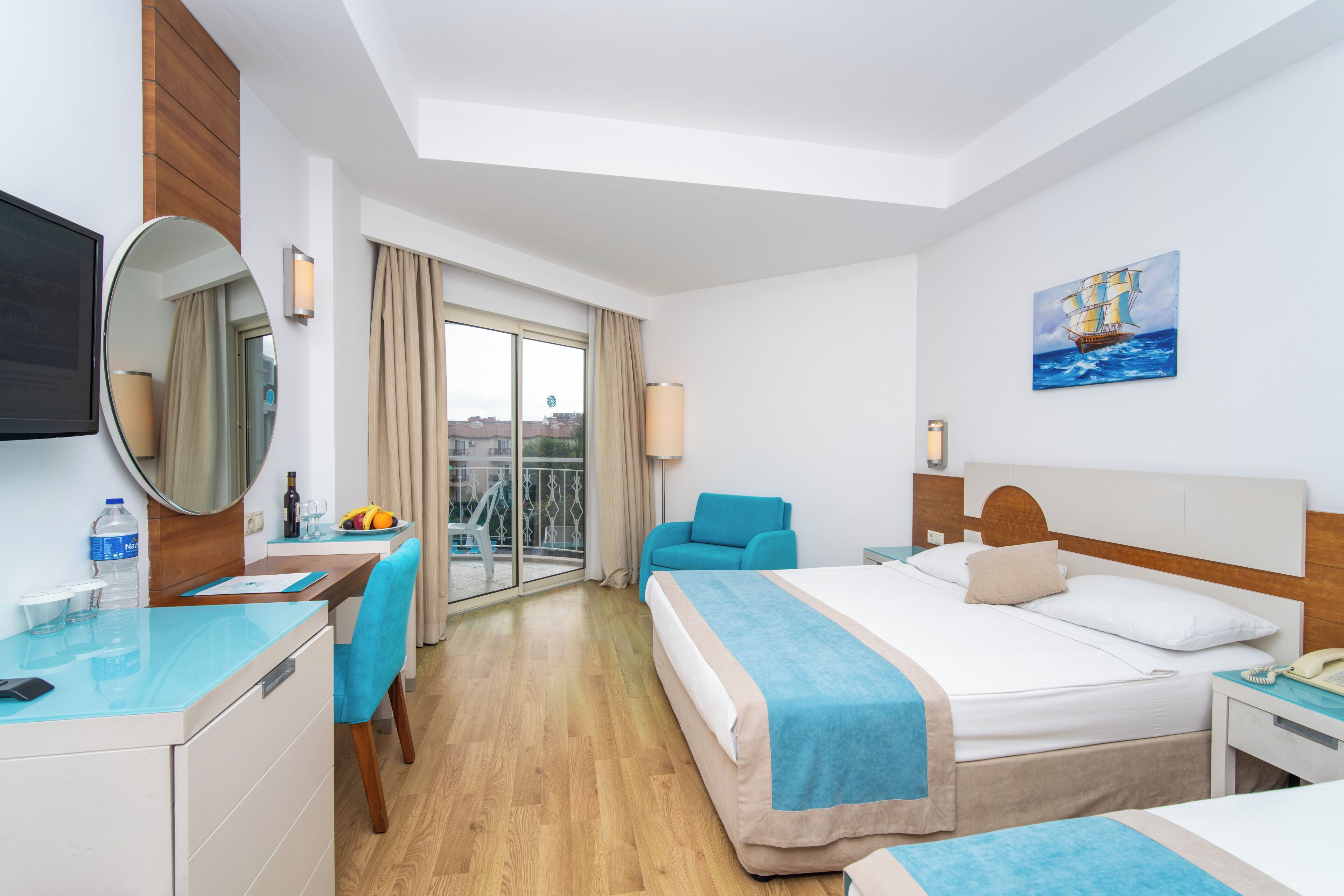 Habitació d'hotel amb llit, escriptori, cadira i una finestra gran amb vistes.
