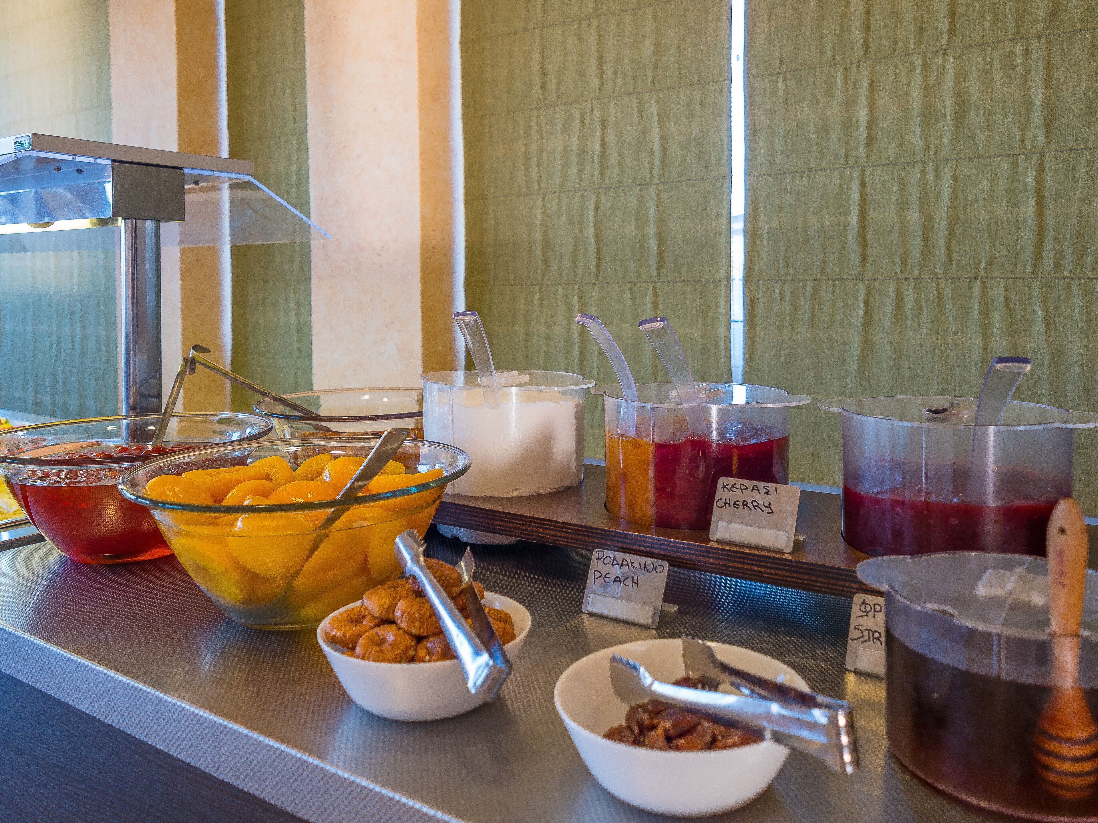 A buffet with various food options including a bowl of fruit, a bowl of nuts, and several containers of different sauces and dips.