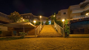 Vista nocturna de una escalera que lleva a un edificio con un área de estar al aire libre techada.
