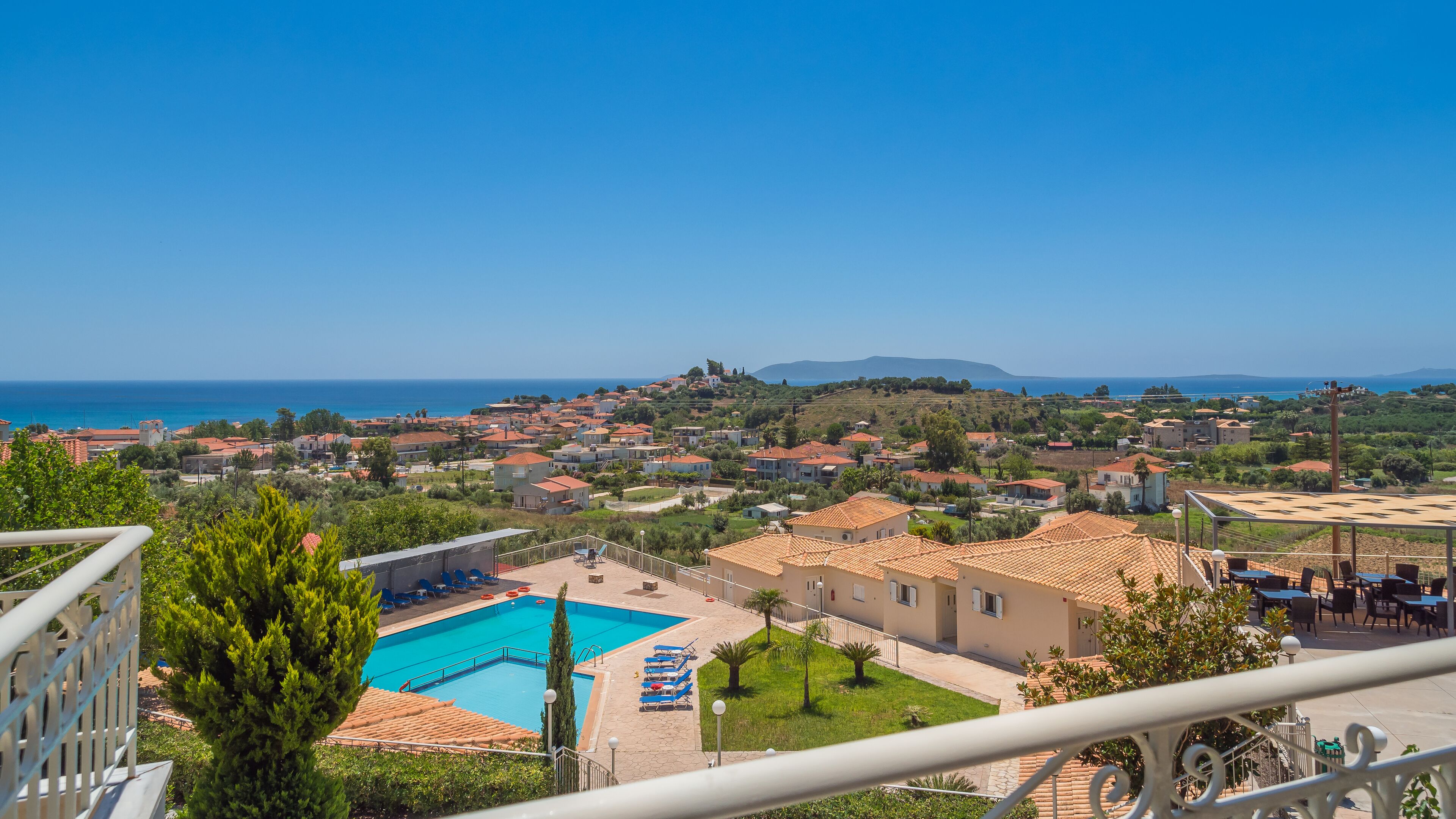 Un pueblo costero con piscina, zona de estar al aire libre y vistas al mar.
