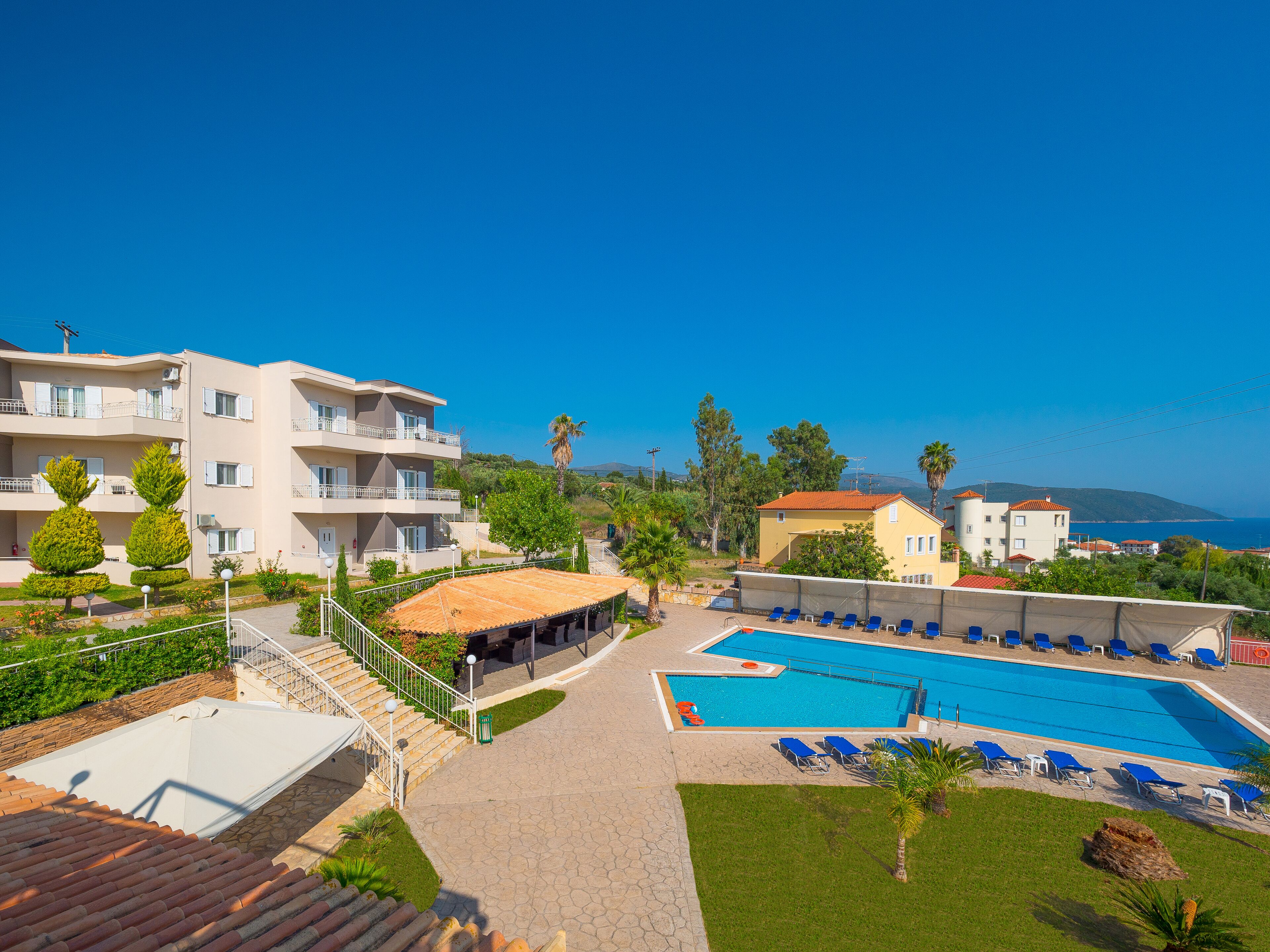 Un hotel con piscina, varios balcones y vistas al mar.