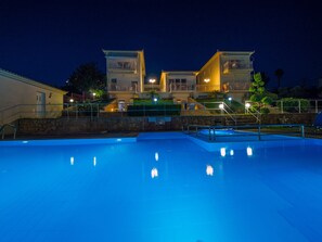 Una piscina con un muro de piedra y escalones que llevan a un edificio con balcones.