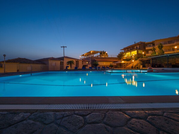 Una piscina con sillones de descanso y una escalera que conduce a un balcón.