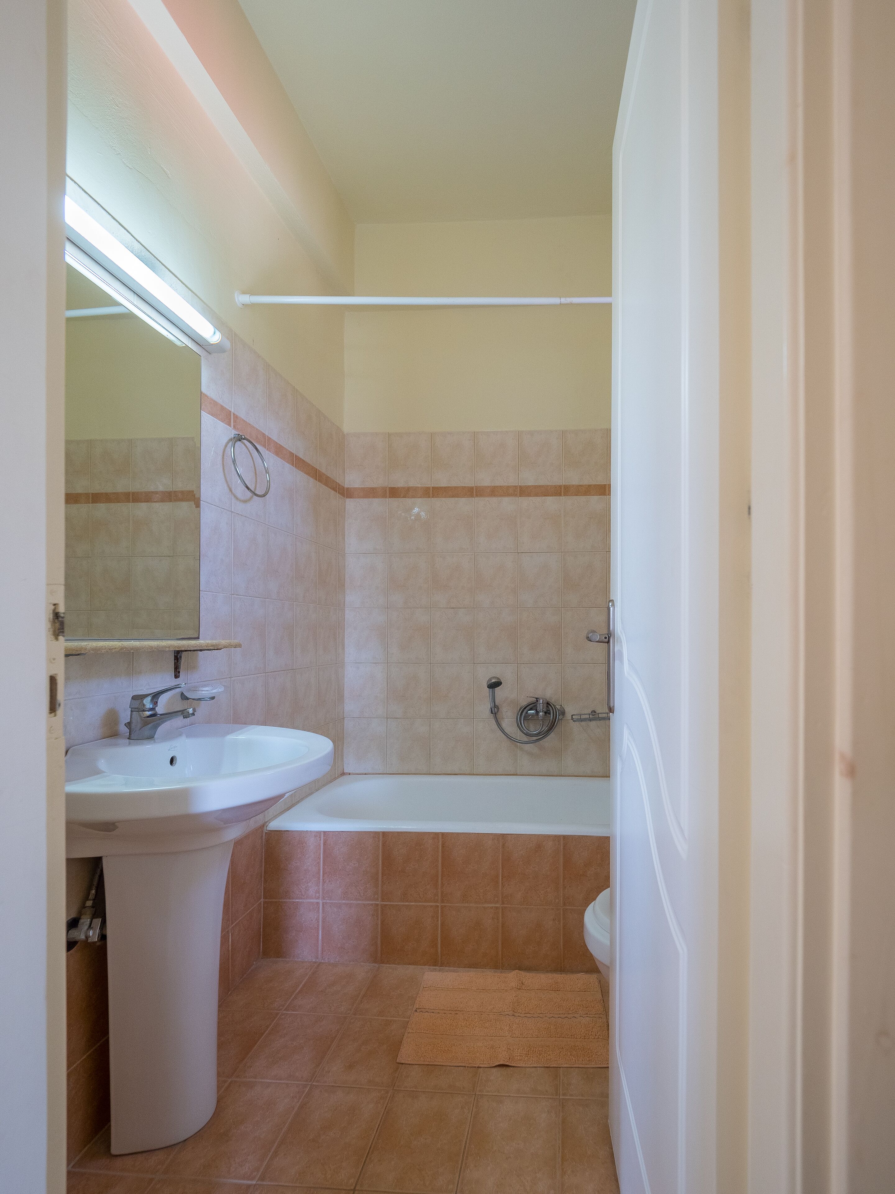A bathroom with a sink, mirror, and bathtub.