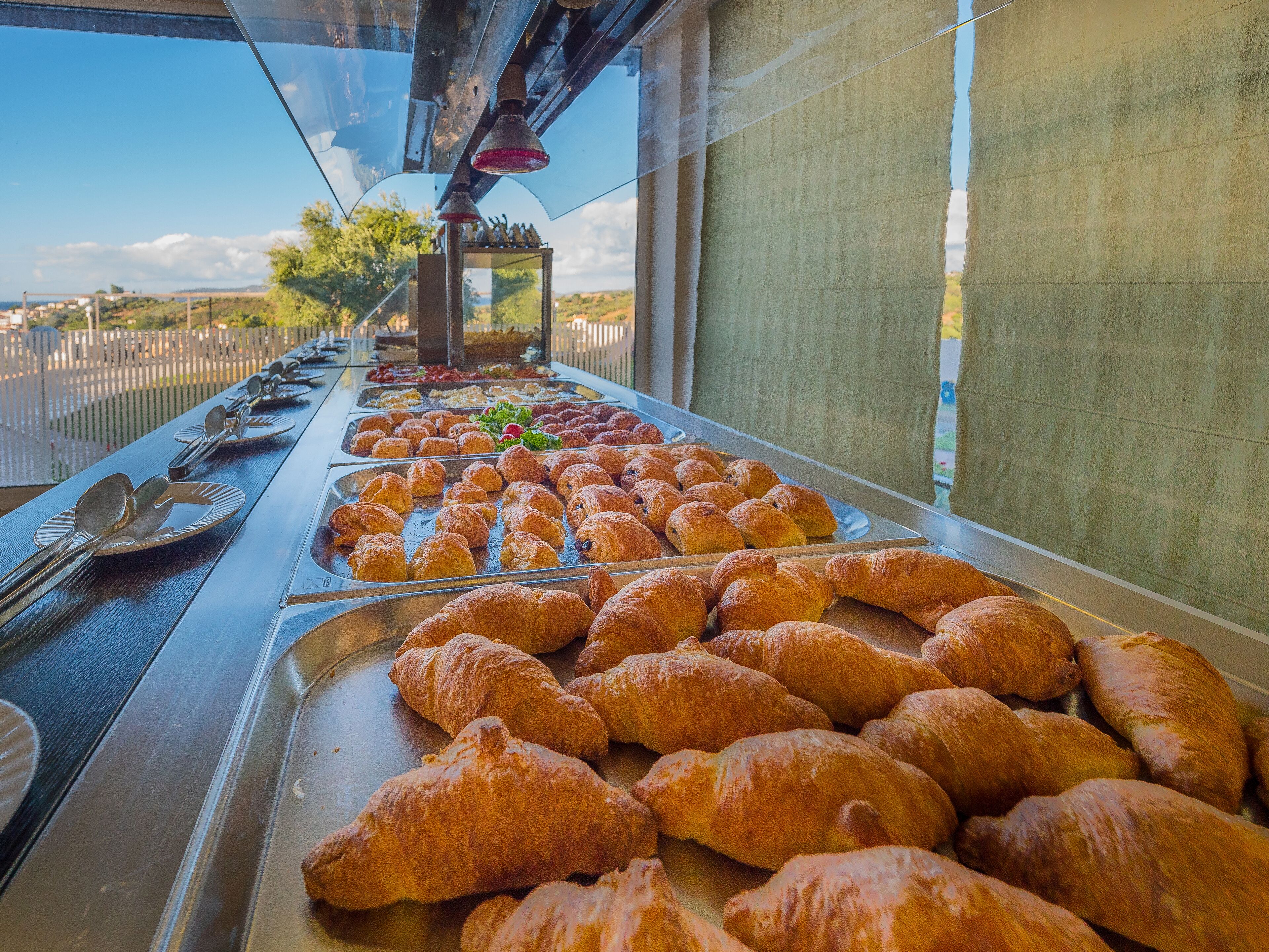 A buffet with various pastries and a view of the outdoors.