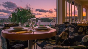 Mesa lista para dos con vistas panorámicas al atardecer a través de amplios ventanales.