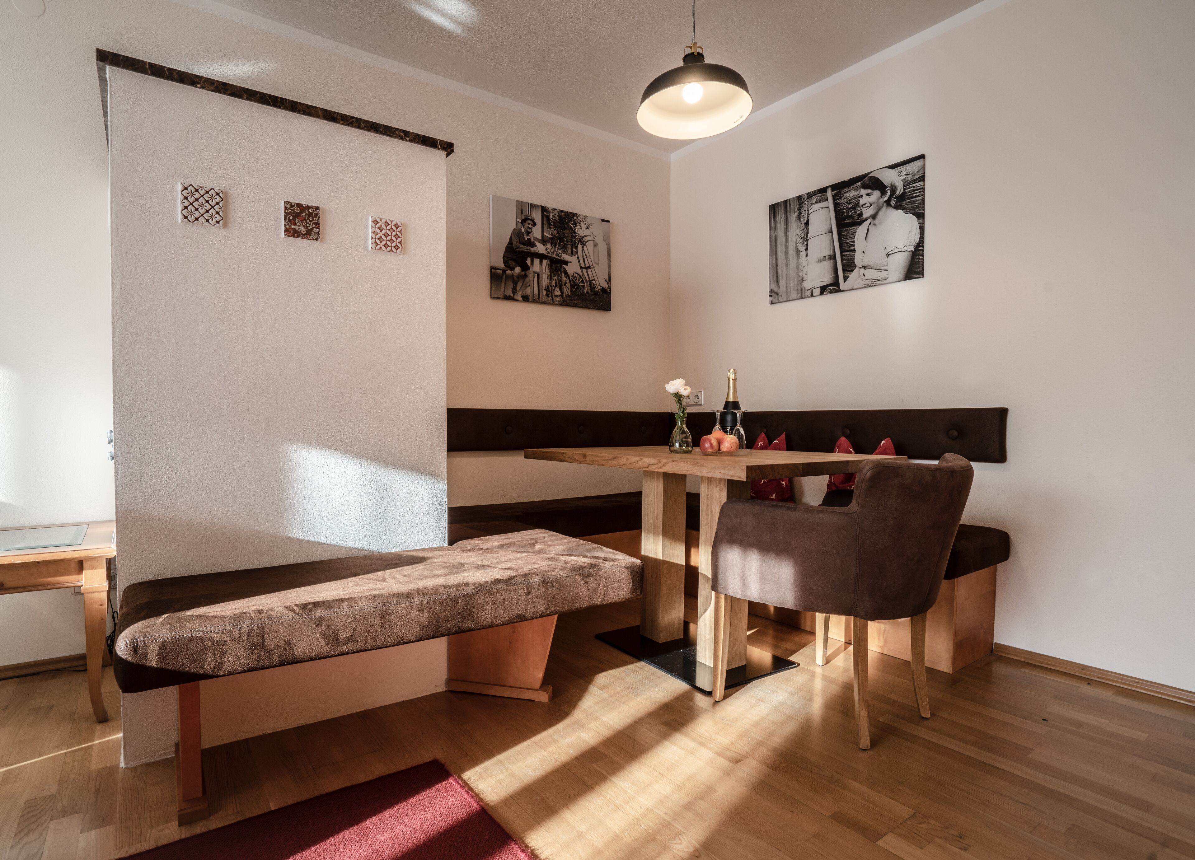 A cozy dining area with a wooden table, cushioned bench, and a pendant light.