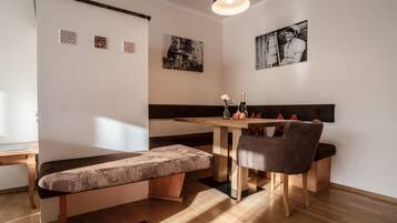 A cozy dining area with a wooden table, cushioned bench, and a pendant light.