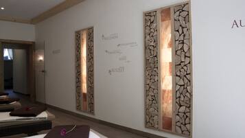 Un pasillo con una recepción, una pared con paneles decorativos y un cartel con texto relacionado con el bienestar.