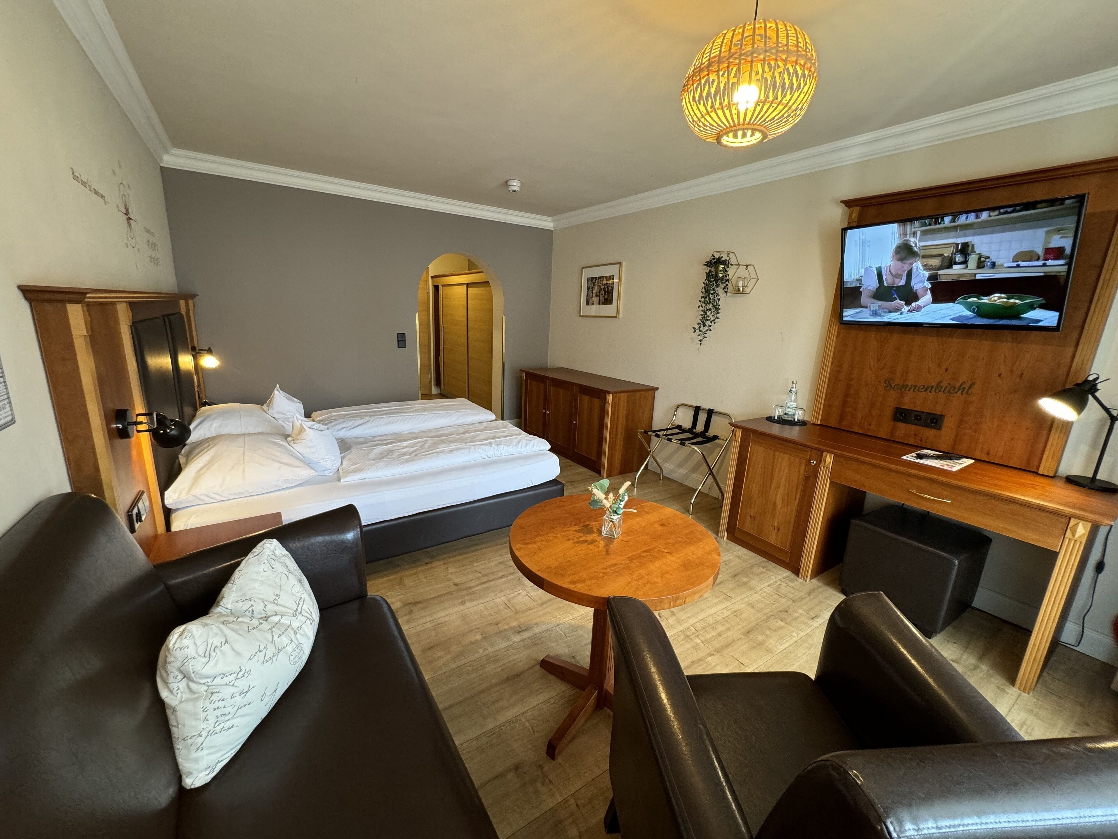 Ein Hotelzimmer mit Bett, Sofa, Schreibtisch, Fernseher und Esstisch.