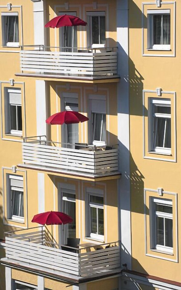 A multi-story building with balconies, some with red umbrellas. - Alpenstadthotels (Bad Reichenhall)