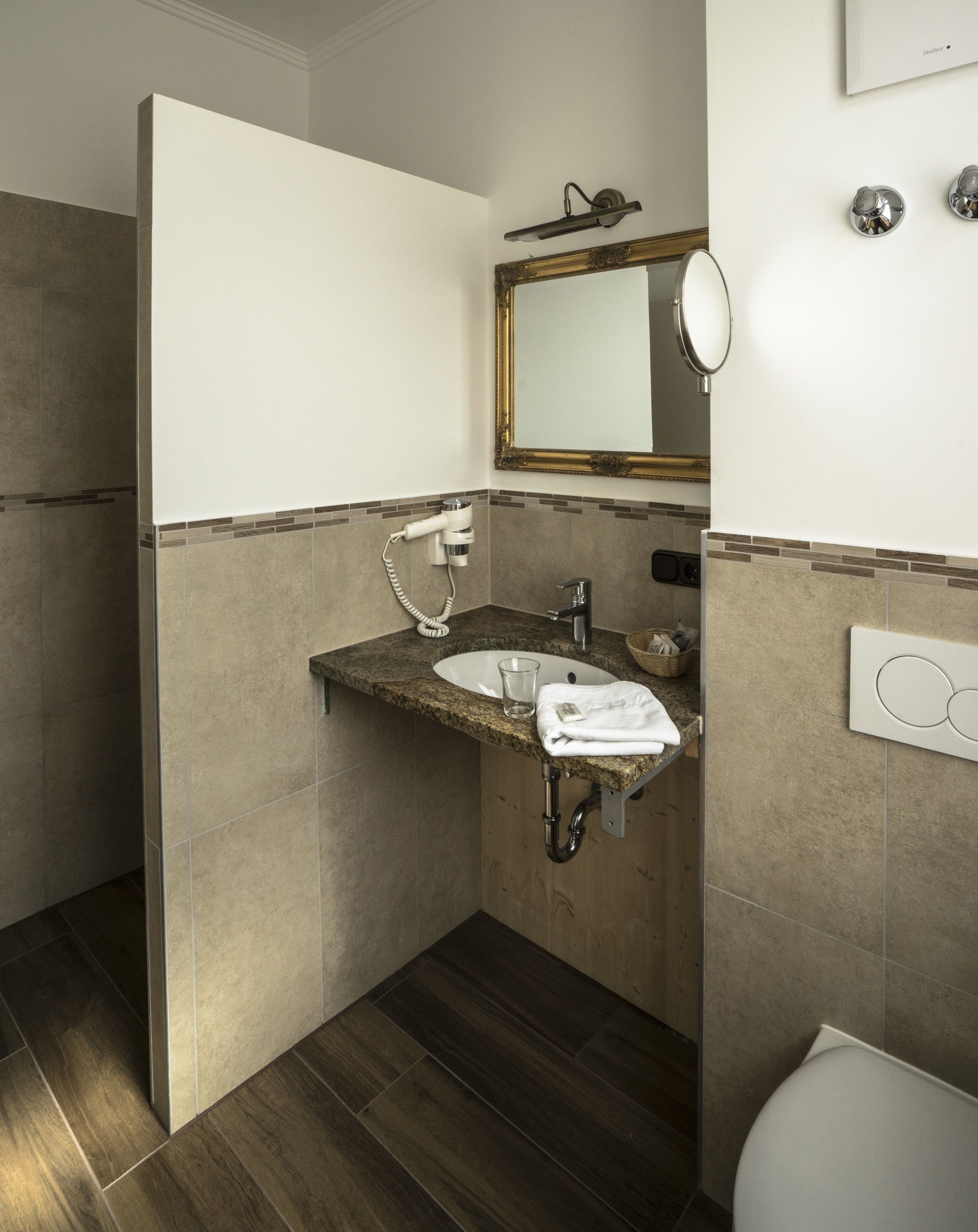 Ein Badezimmer mit Granitwaschtisch, Spiegel, Handtuch und Toilette.