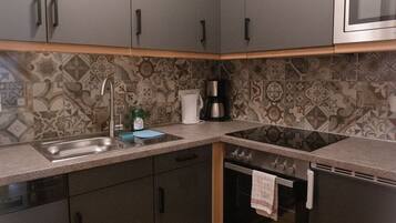 A compact kitchen with grey cabinets, a microwave, a stove, and a sink.
