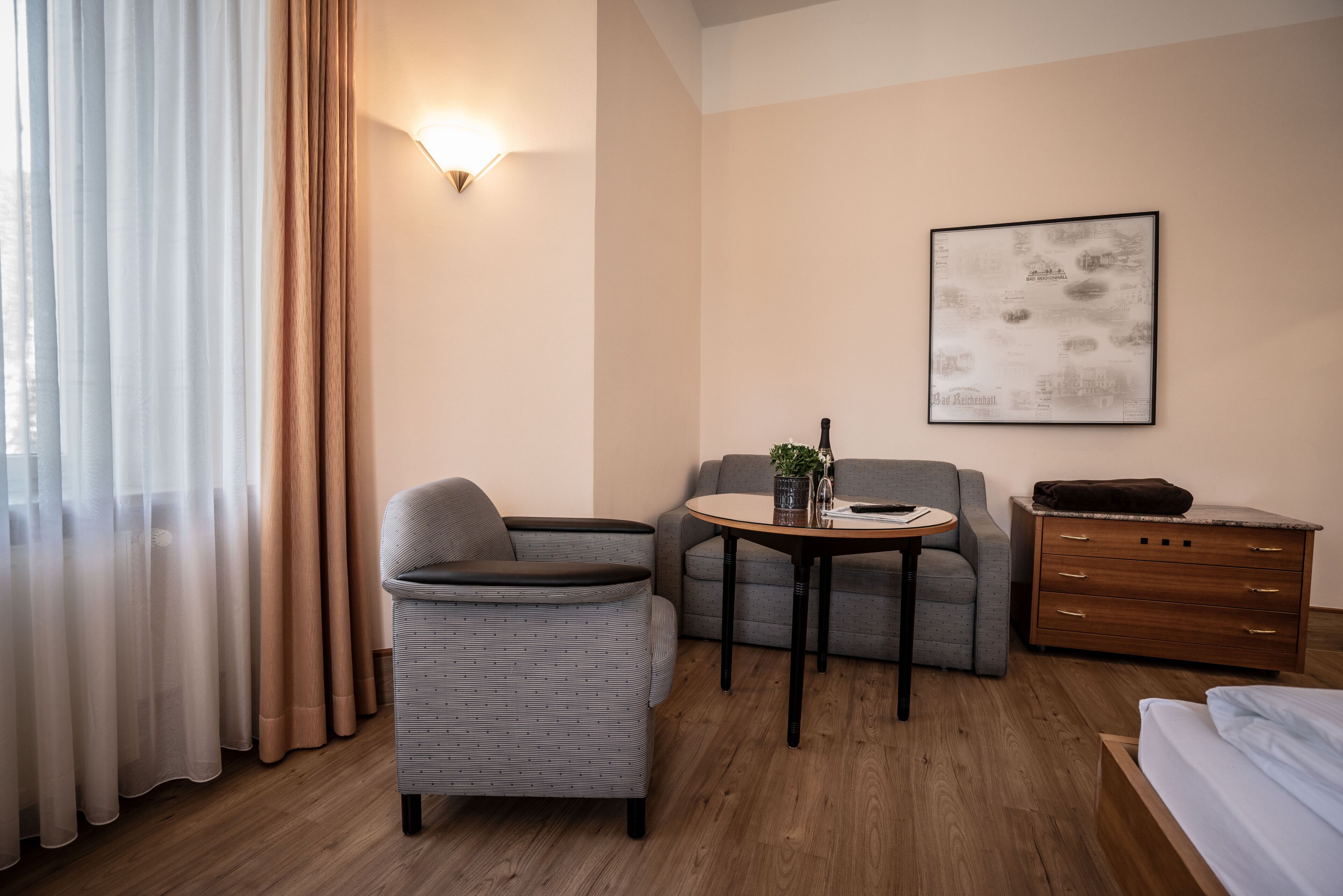 Ein Hotelzimmer mit Sofa, Sessel, kleinem Tisch und einem Bett.