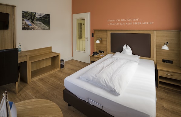 A hotel room with a bed, bedside tables, a desk, a chair, and a painting on the wall. - Alpenstadthotels (Bad Reichenhall)