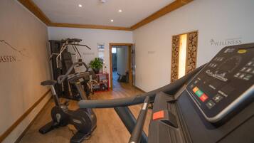 A gym with exercise equipment, wooden beams on the ceiling, and a wall with the text "AUSSEN...".