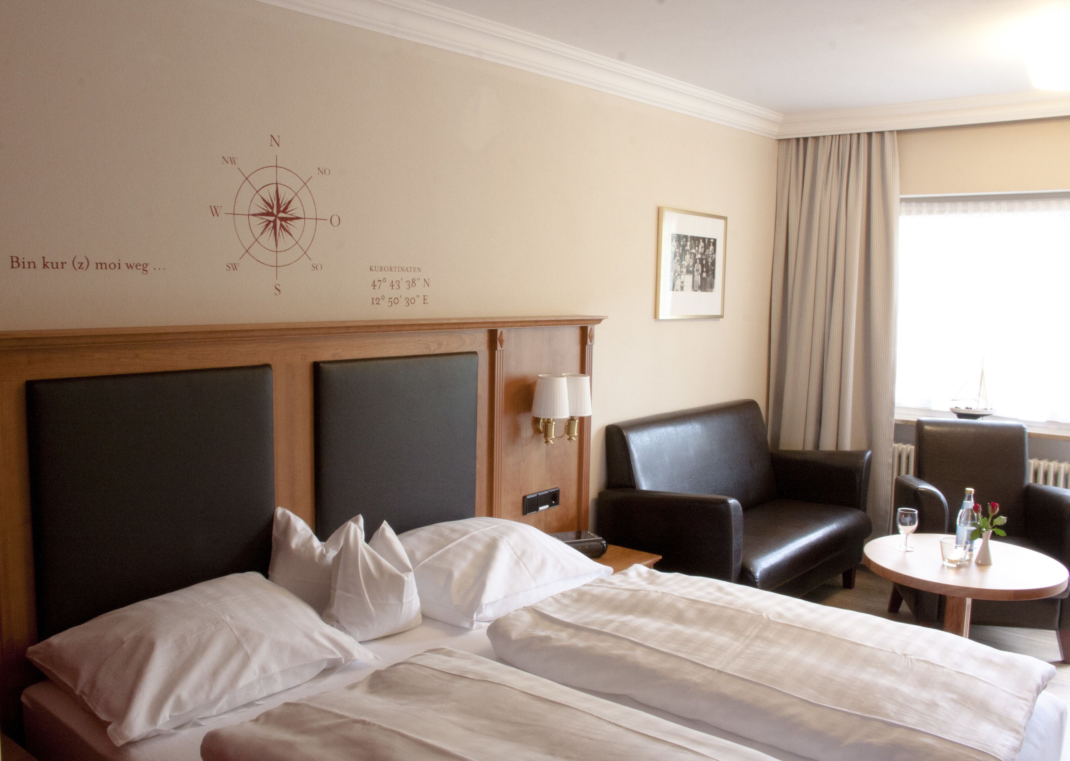 Ett hotellrum med en stor säng, ett skrivbord, en stol och ett litet bord med en lampa.