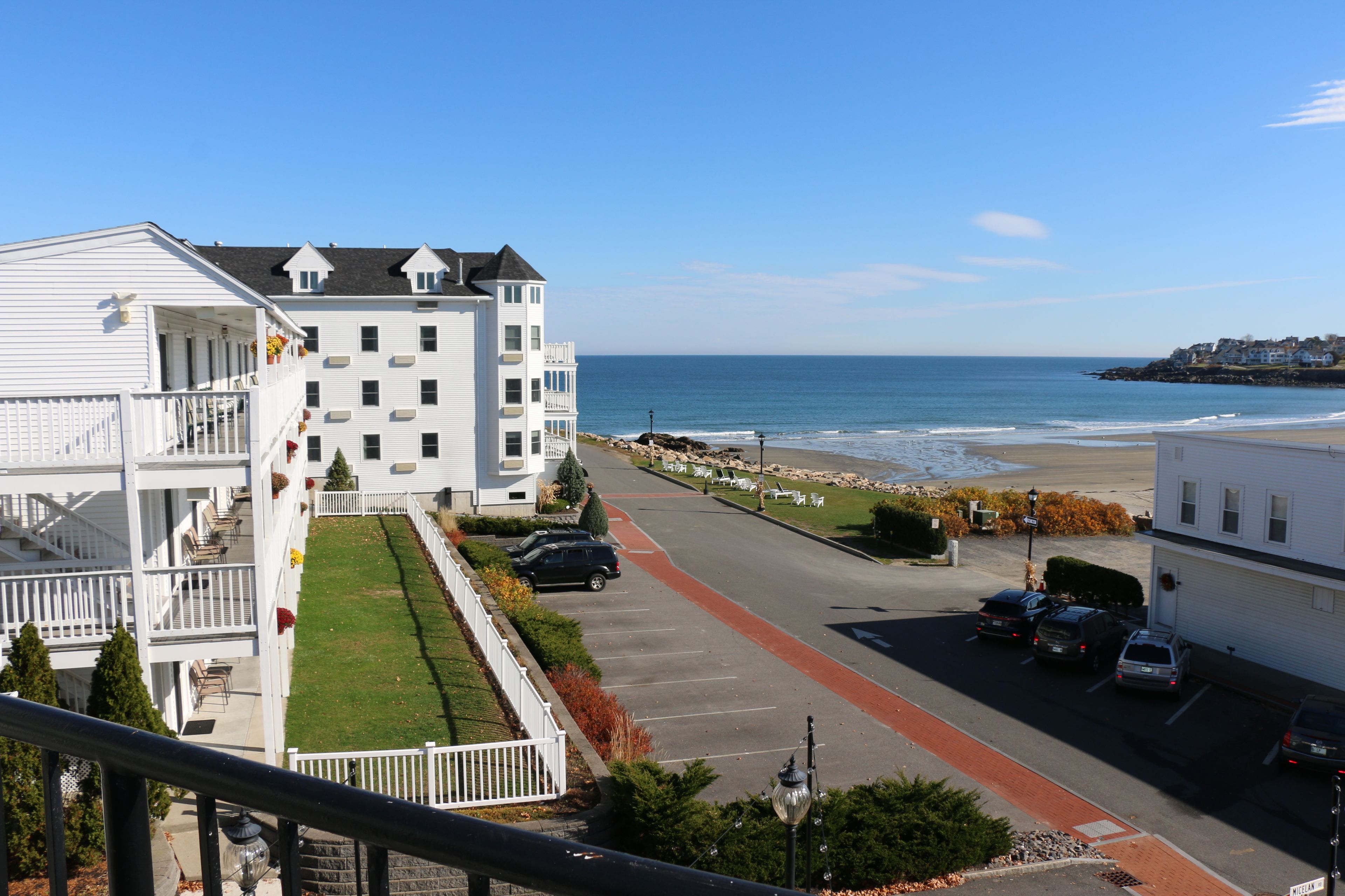 A coastal residential area with a white building featuring balconies and a red pathway.