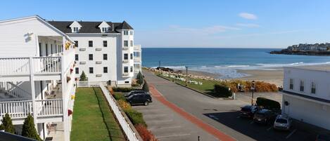 A coastal residential area with a white building featuring balconies and a red pathway.