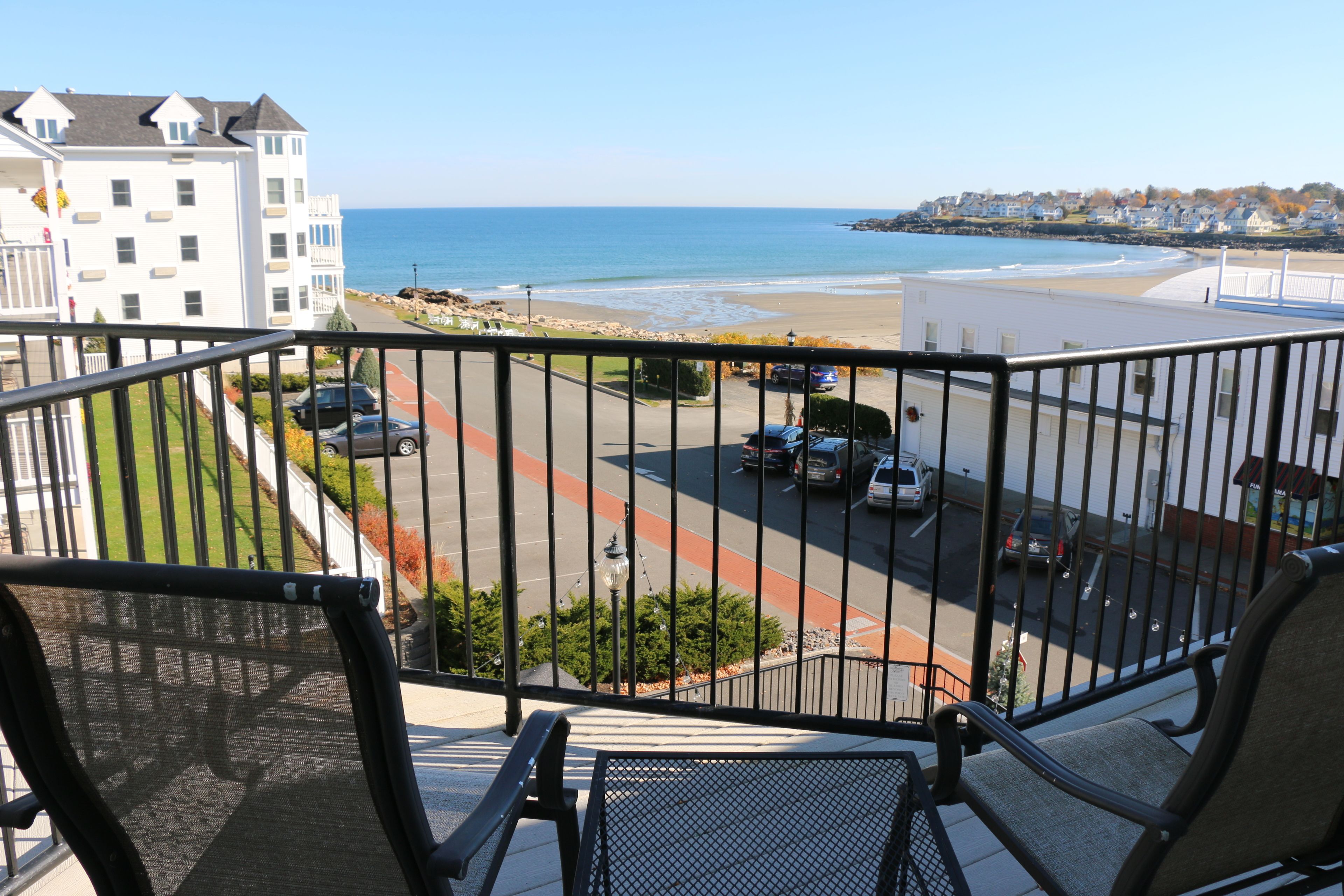 A balcony with a view of a beach and parking area.