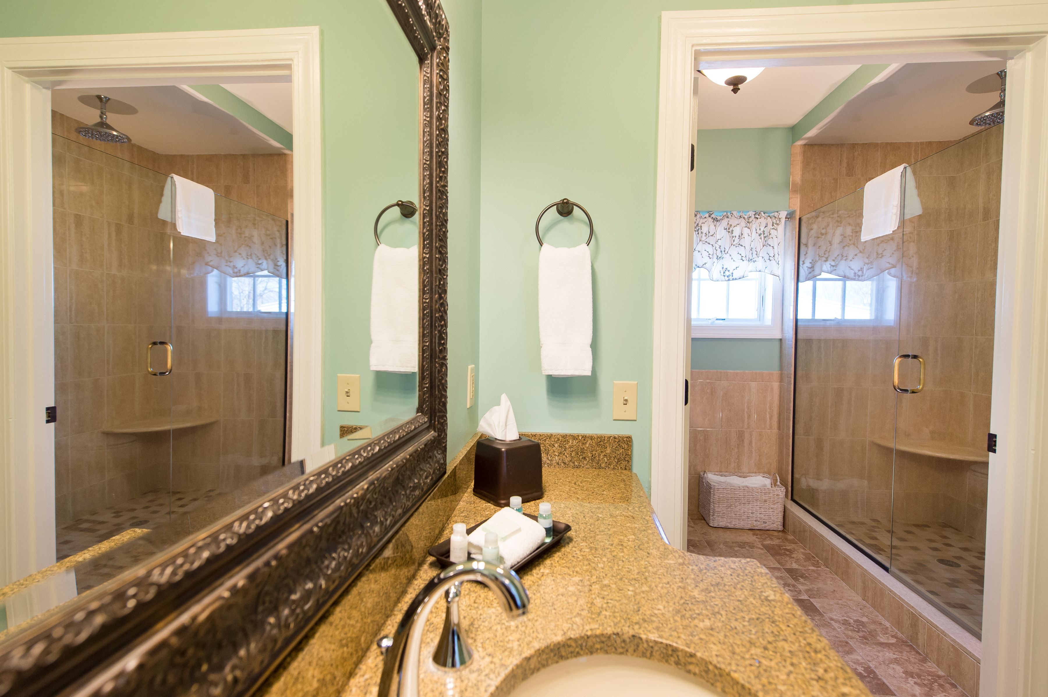 A bathroom with a large mirror, a sink, a towel rack, and a shower area.