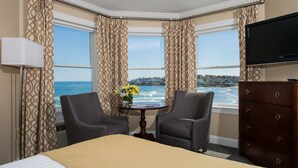 A hotel room with a bed, two armchairs, a small table with flowers, a dresser, and a TV. - Union Bluff Hotel & Meeting House (York Beach)