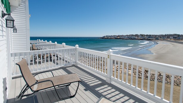 A wooden deck with a white railing overlooking a beach. - Union Bluff Hotel & Meeting House (York Beach)