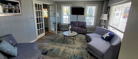 A living room with two sofas, a coffee table, and a TV mounted on the wall.