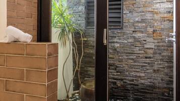 Un baño moderno con puerta de cristal, ducha y planta en maceta.
