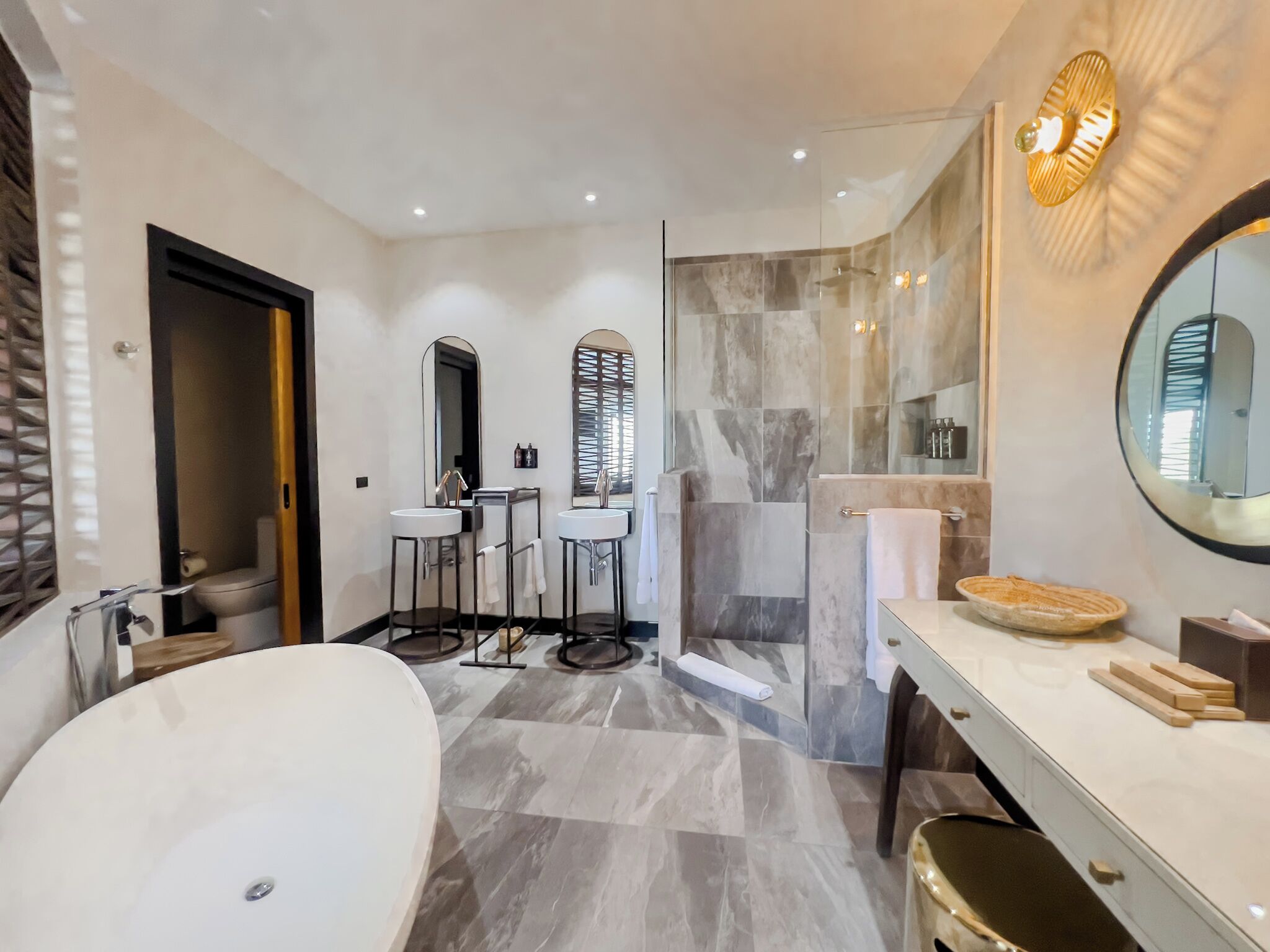 A modern bathroom with a freestanding bathtub, two sinks, a large mirror, and a shower area.