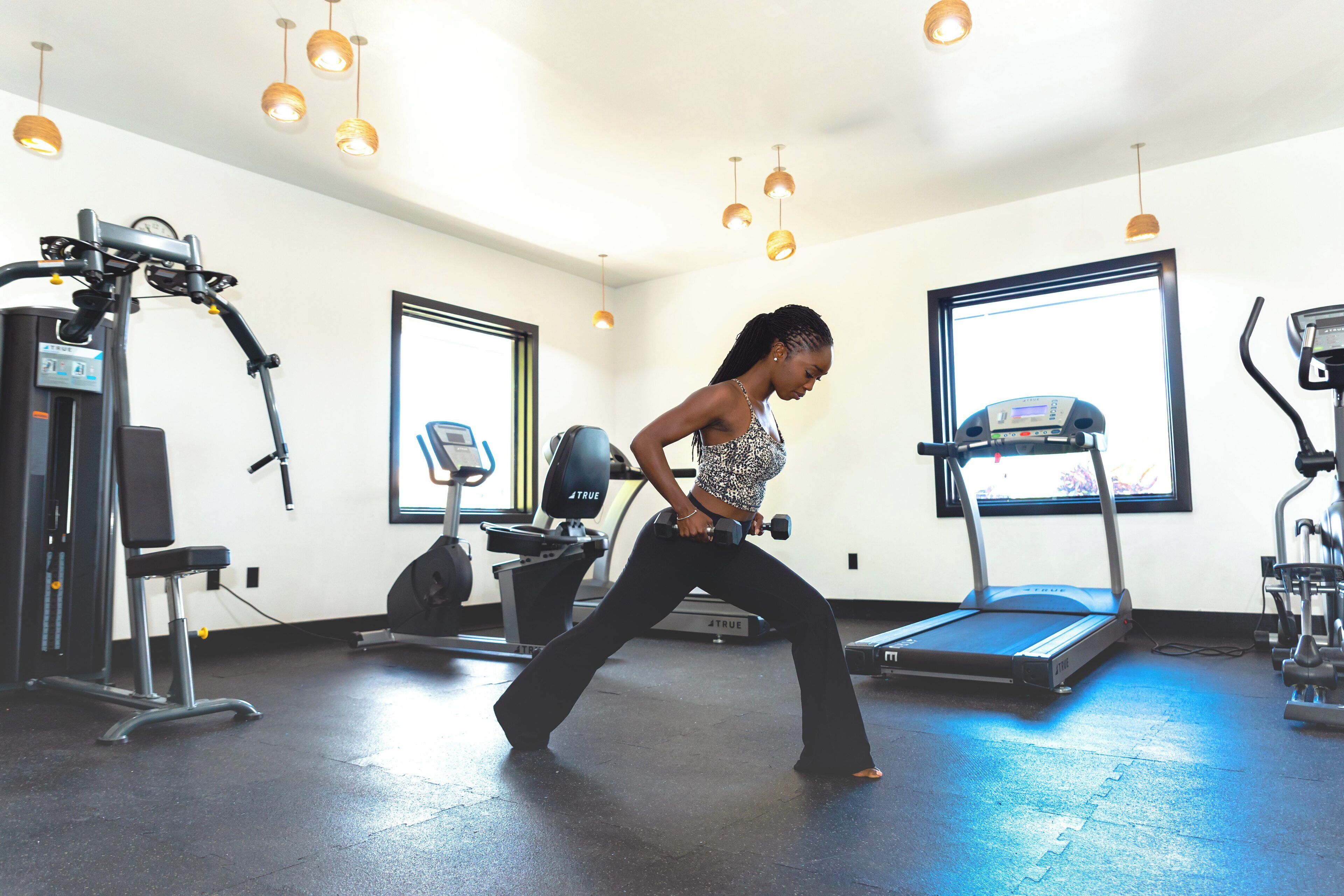 A gym with exercise equipment, a treadmill, and a window providing natural light.