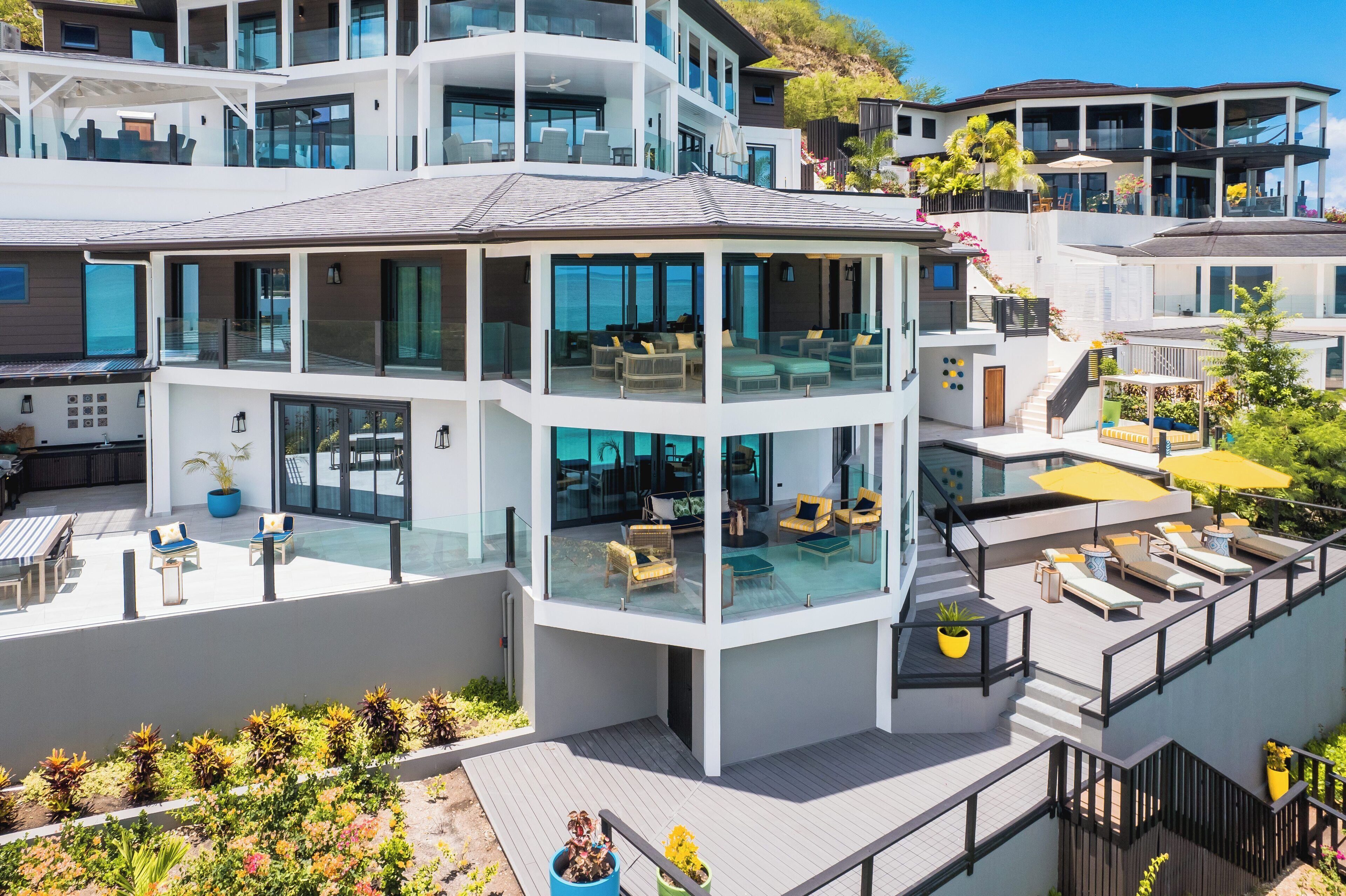 A modern multi-story building with a glass-enclosed upper level, outdoor seating, and a pool area.