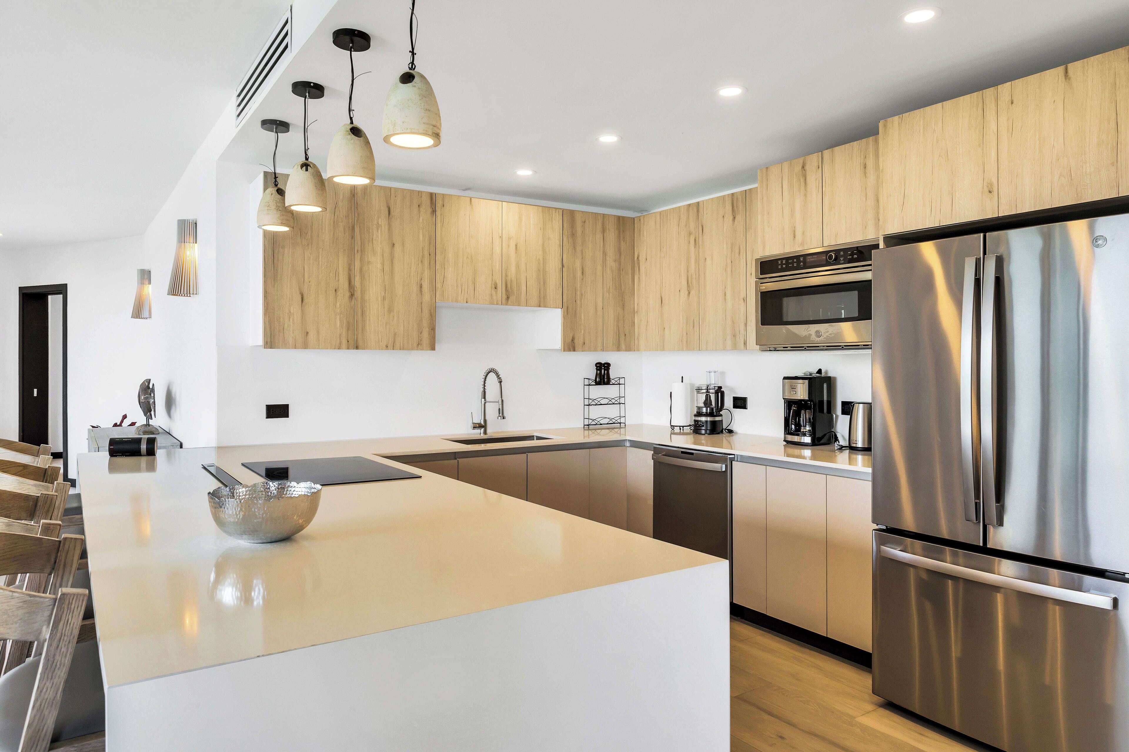A modern kitchen with a central island, stainless steel appliances, and wooden cabinetry.