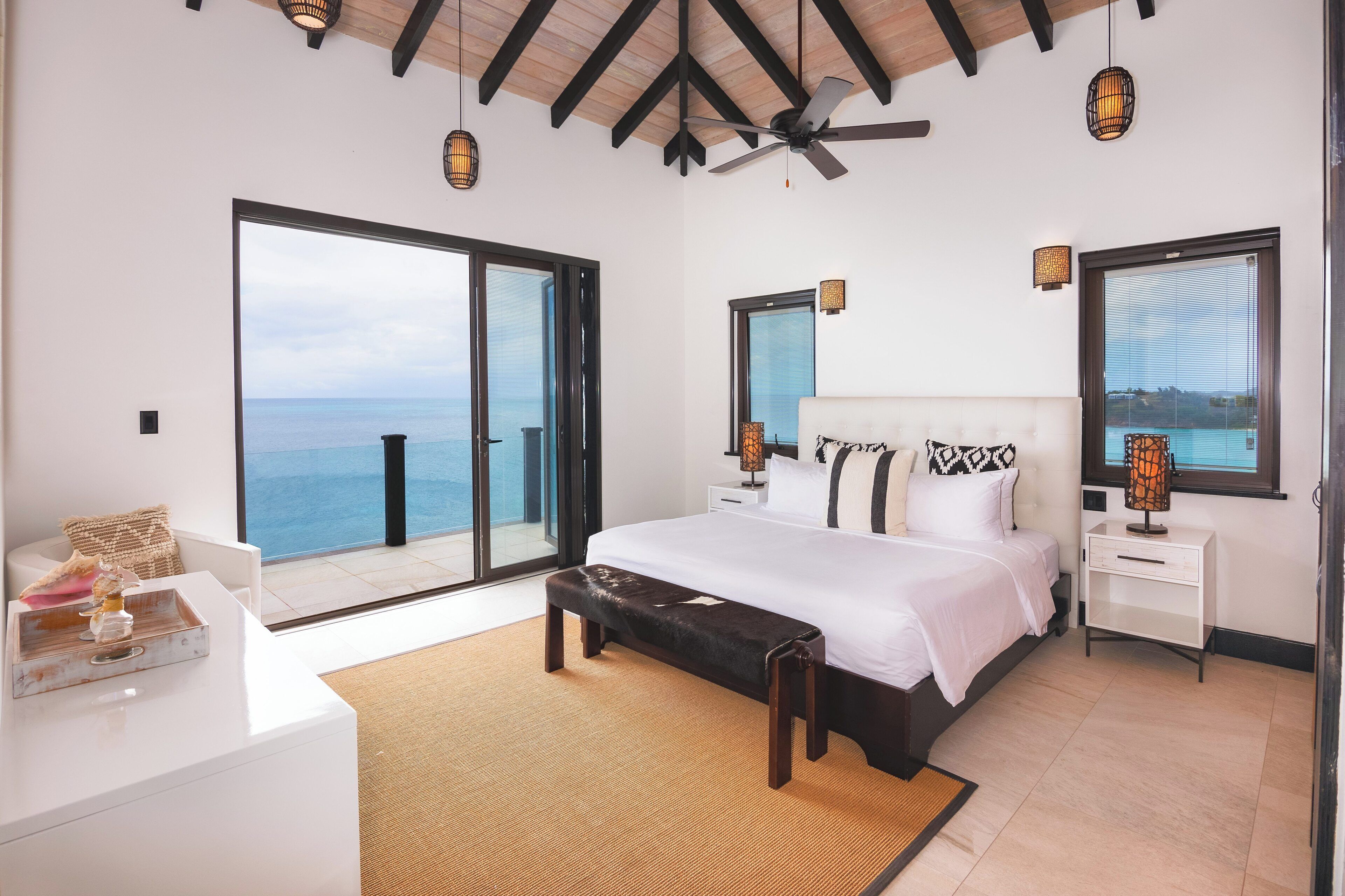 Ein Schlafzimmer mit einem großen Bett, einer Bank, einem Schreibtisch und Meerblick.