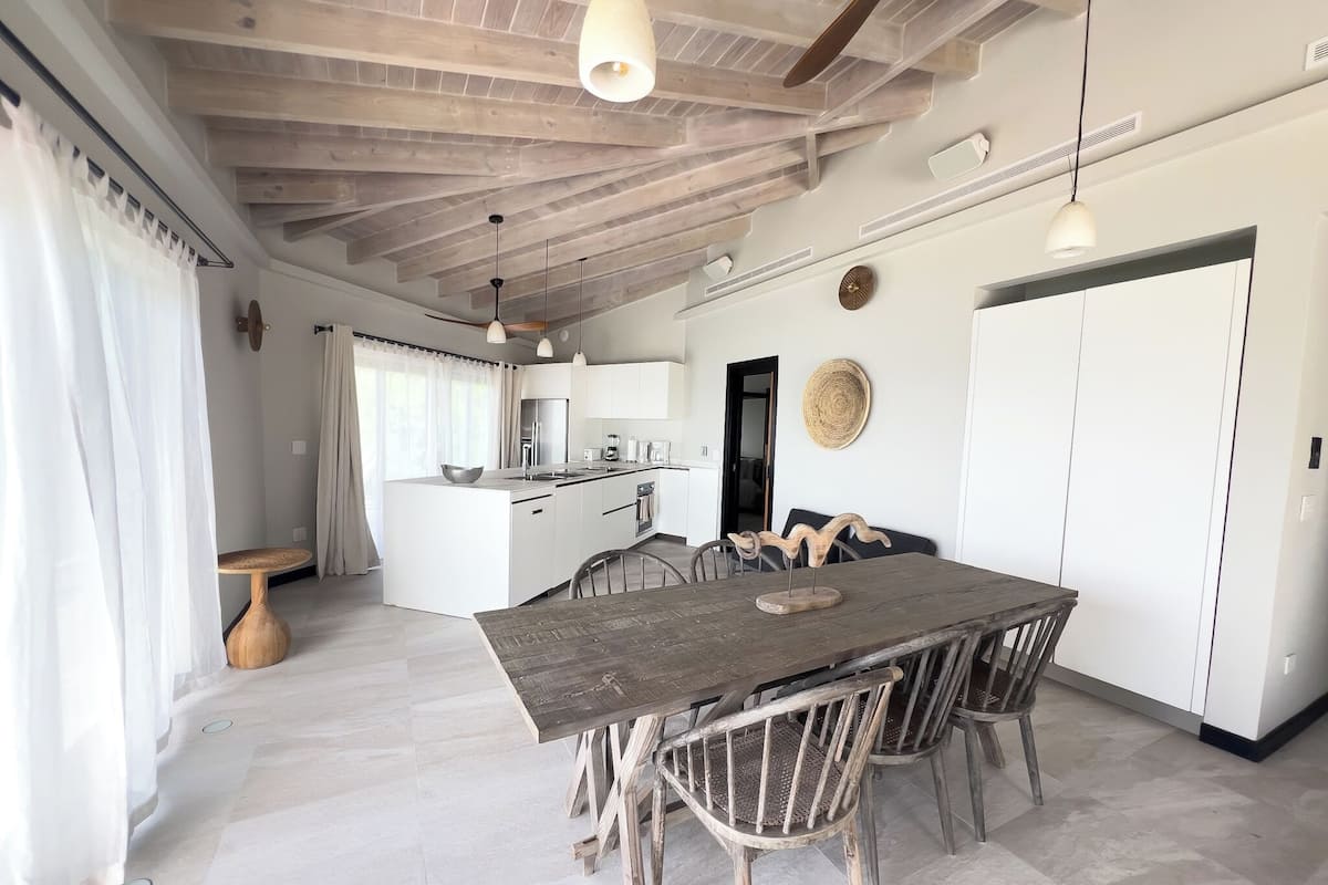 A spacious kitchen with white cabinets, a central island, and a dining area with a wooden table and chairs.