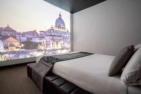 A hotel room with a large window displaying a cityscape view.