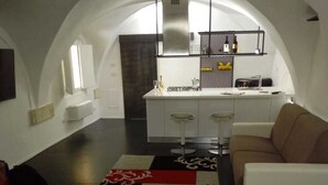 A modern interior with a kitchen, white bar stools, a sofa, and a patterned rug. -  Gueshouse o Affitacamere Magenta Campo dei Fiori  (Rome)